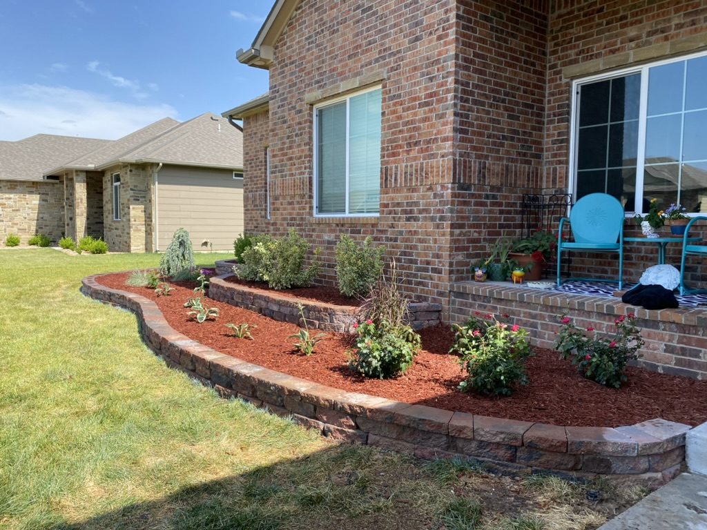 Close view of the tiered beds with red mulch, roses and new plantings